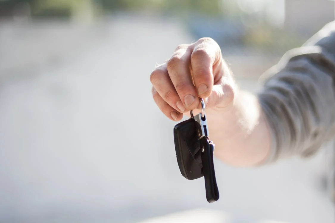 Car keys being passed from one person's hand to another